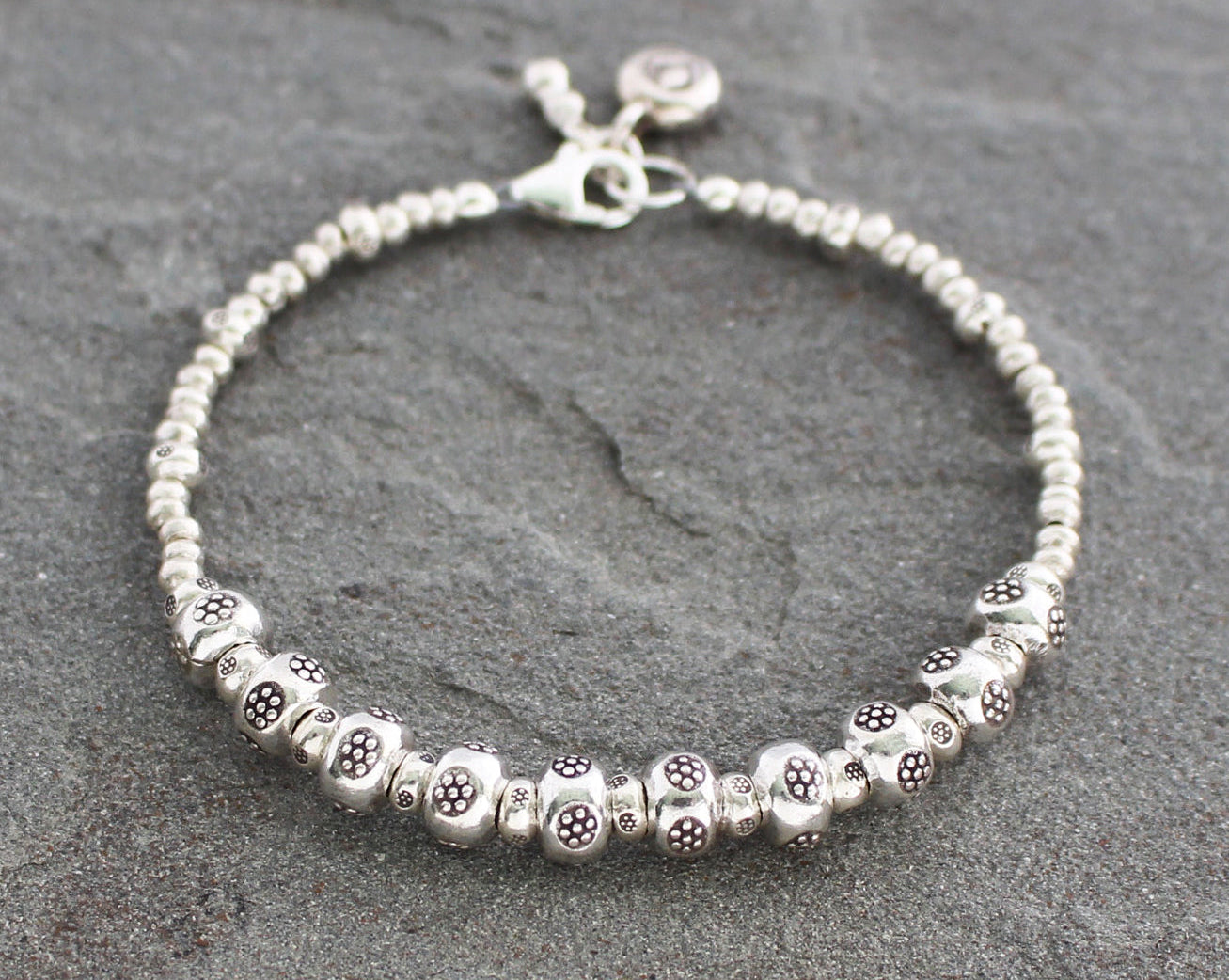Silver beaded bracelet on a gray stone surface