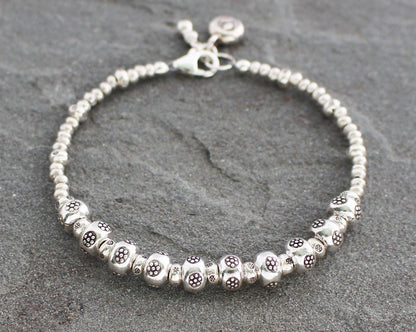 Silver beaded bracelet on a gray stone surface